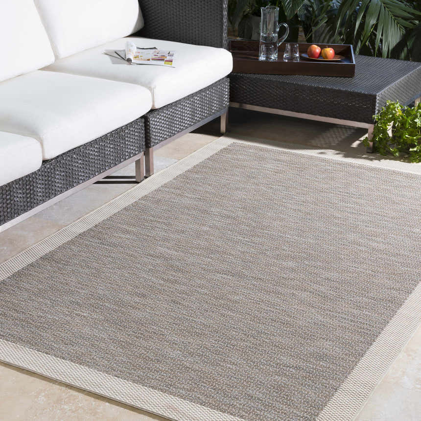 Outdoor patio scene with a taupe and cream Escalon Area Rug, wicker sofa, and coffee table. Roomscene-Rectangle