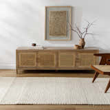 Living room scene with a Nimai Cream Wool Area Rug, wood cabinet, and modern chair on a wood floor. Roomscene-Rectangle