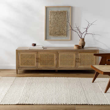 Living room scene with a Nimai Cream Wool Area Rug, wood cabinet, and modern chair on a wood floor. Roomscene-Rectangle