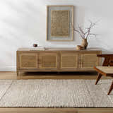 Living room scene with a beige Nimai Wool Area Rug, wood console table, and modern chair. Roomscene-Rectangle