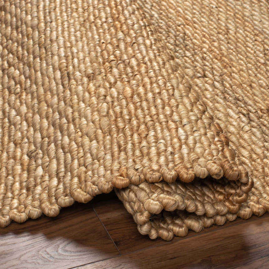 Close-up of the hand woven Olof Jute Rug in natural jute on a wood floor, showing texture and detail. Fold