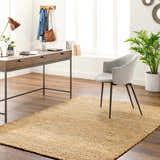 Home office with Olof Hand Woven Jute Rug, wood desk, gray chair, and plant. Natural light and neutral tones create a calm workspace. Roomscene-Rectangle