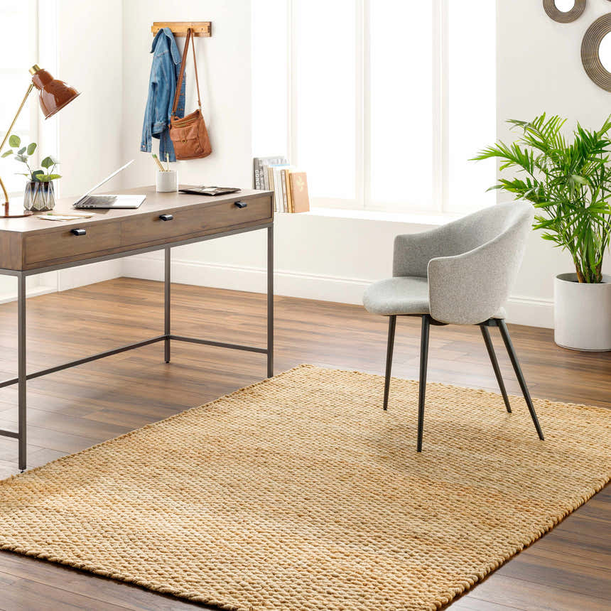 Home office with Olof Hand Woven Jute Rug, wood desk, gray chair, and plant. Natural light and neutral tones create a calm workspace. Roomscene-Rectangle