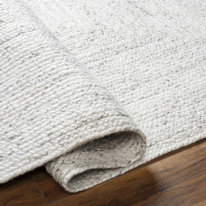 Close-up of the hand woven Kenyi Rose Cream Area Rug showing beige, gray, and white tones and textured weave. Fold