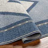 Close-up of the Onan Area Rug showing its arctic sky, gray, and silver geometric pattern and machine-woven texture. Fold