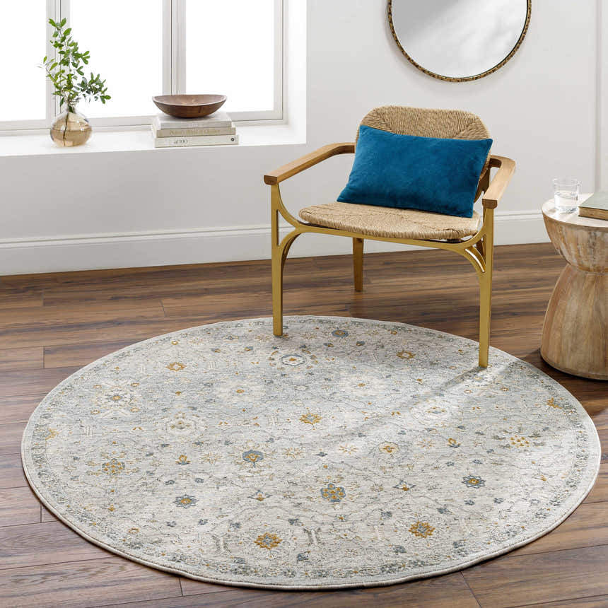 Light-filled room with round Annie Green Textured Rug, woven chair with blue pillow, and wood accents. Roomscene-Round