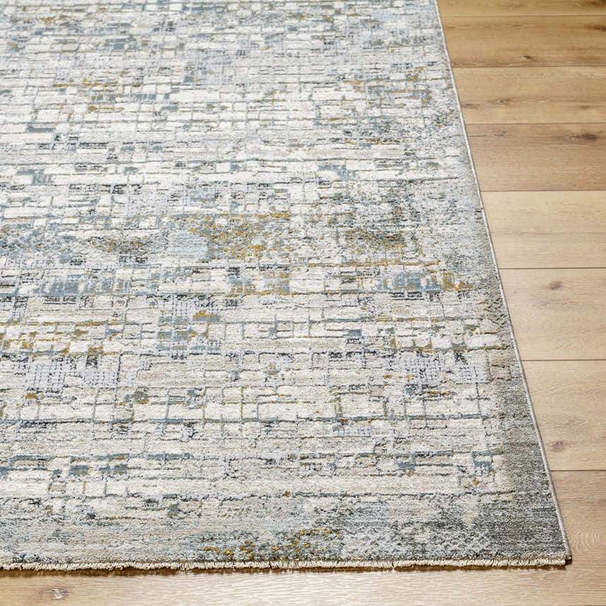Close-up of the Chaka Textured Rug. Abstract pattern in off-white, gray, blue, and mustard on a wood floor. Front