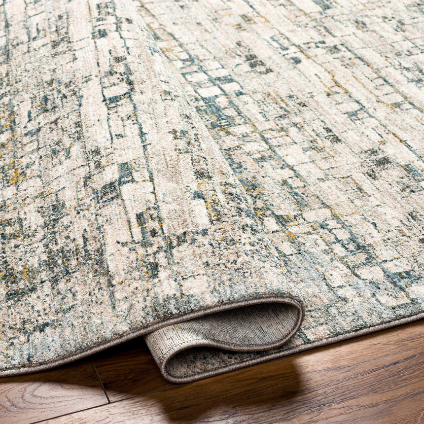 Close-up of the Chaka Textured Rug. Features a contemporary abstract pattern in dusty sage, ink blue, and off-white. Fold