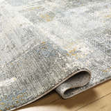 Close-up of the Elina Textured Abstract Rug. Colors include dusty sage, ink blue, and mustard. Contemporary style. Fold