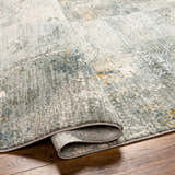 Close-up of the Elina Textured Abstract Rug showing the dusty sage, blue, and mustard colors and textured weave. Fold