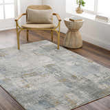 Living room scene with Elina Textured Abstract Rug in gray, blue, and mustard colors, styled with a chair and side table. Roomscene-Rectangle