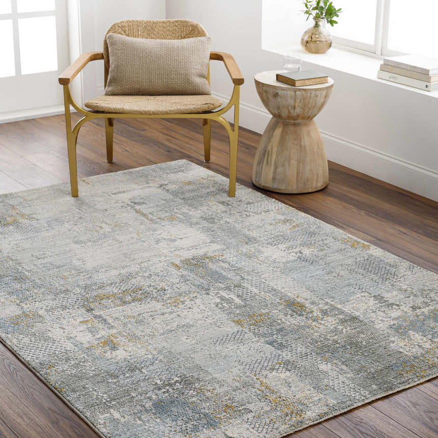 Living room scene with Elina Textured Abstract Rug in gray, blue, and mustard colors, styled with a chair and side table. Roomscene-Rectangle