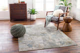 Living room scene with a gray chair, wood accents, and the Elina Textured Abstract Rug in dusty sage, blue, and gray. Roomscene-Rectangle