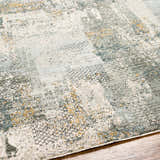 Close-up of the Elina Textured Abstract Rug. Features dusty sage, ink blue, mustard, and gray tones. Texture