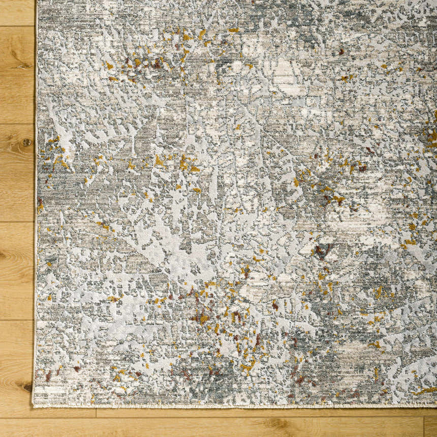 Close-up of Moke Textured Rug with Fringes. Abstract design in gray, light gray, and gold tones on a soft polyester rug. Corner