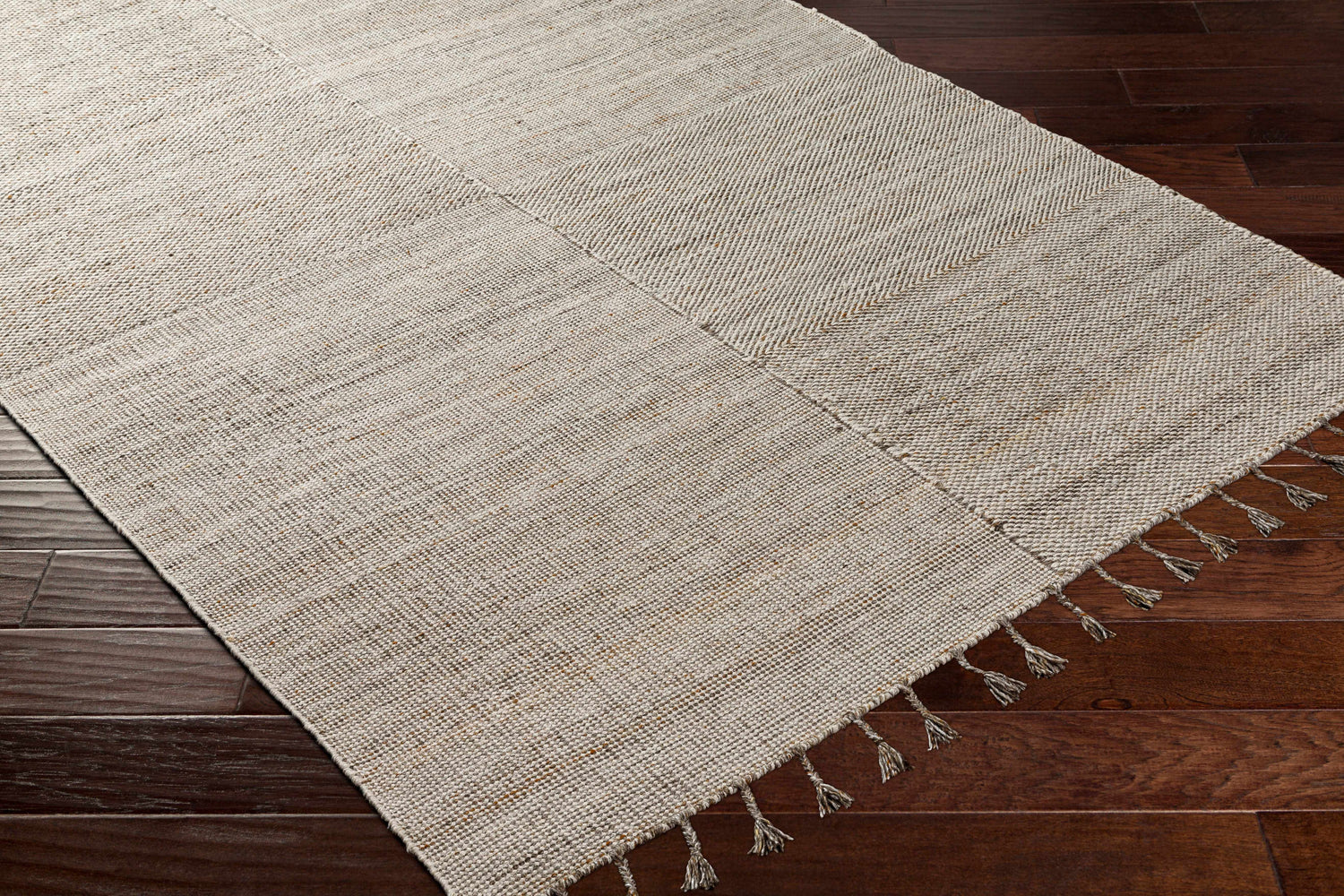 Close-up of the hand-woven Anaya Beige Area Rug on dark wood floors, showing texture and tassels. Corner