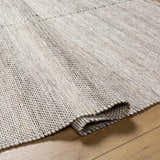 Close-up of the hand woven Anaya Beige Area Rug showing texture and neutral beige, black, and bone colors. Fold