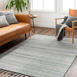 Living room scene with a cream and blue Anaya Area Rug, leather sofa, and wood chair. Roomscene-Rectangle