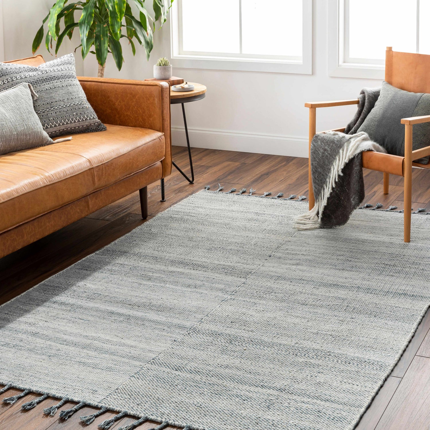 Living room scene with a cream and blue Anaya Area Rug, leather sofa, and wood chair. Roomscene-Rectangle