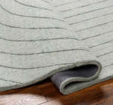 Close-up of the hand-loomed Ayumi Area Rug. The wool rug has a subtle gray striped pattern and a soft, inviting texture. Fold