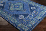 Close-up of the Selden Area Rug, a blue rug with a geometric pattern and a soft, textured pile. Corner
