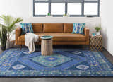 Living room scene with a blue Selden Area Rug, brown leather sofa, and natural wood accents. Roomscene-Rectangle