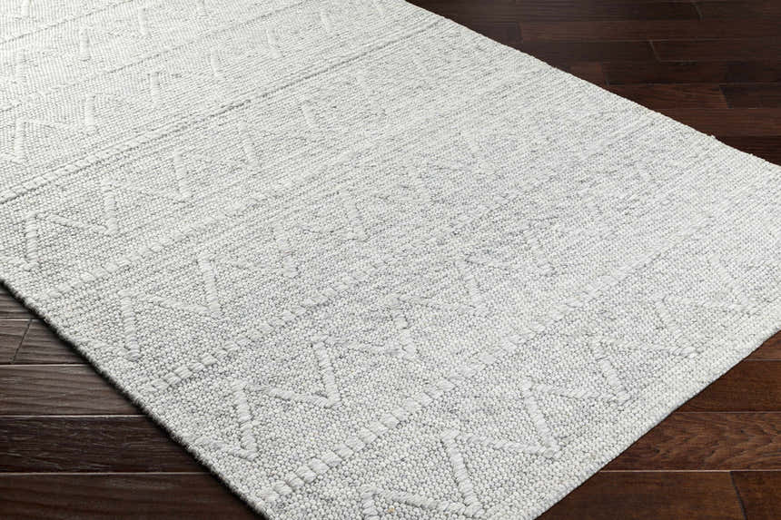 Close-up of the hand woven Kyung Gray Area Rug showing its light gray color and geometric pattern. Corner