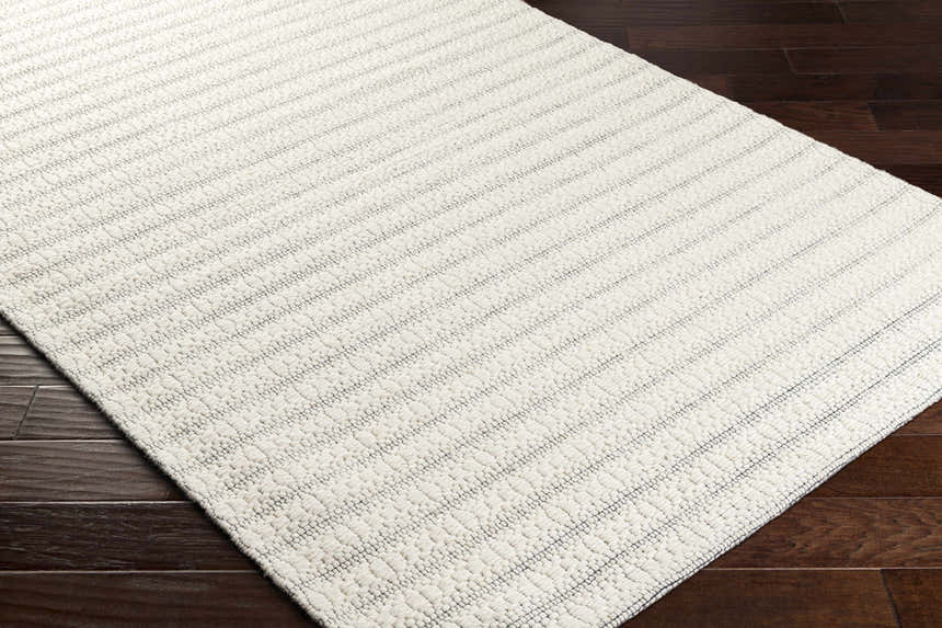Close-up of the hand-woven Laleh Cream Area Rug showing its beige color, subtle pattern, and textured wool blend. Corner