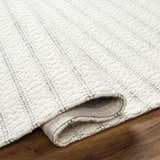 Close-up of the Laleh Cream Area Rug showing its woven texture, beige color, and geometric stripe pattern. Fold