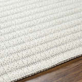 Close up of the textured, hand woven Laleh Cream Area Rug on hardwood floor. Texture