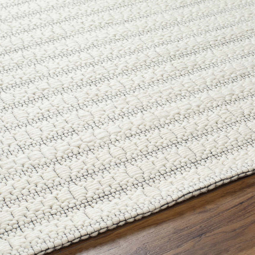 Close up of the textured, hand woven Laleh Cream Area Rug on hardwood floor. Texture