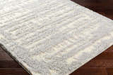 Close-up of the plush Gidja Gray Area Rug showing its soft texture and subtle beige and gray geometric pattern. Corner