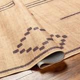 Close-up of the Fathi Washable Area Rug. Camel and dark brown geometric pattern on a woven, recycled fabric texture. Fold