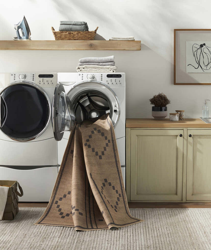 Laundry room with Fathi Washable Area Rug in camel and brown partially inside the washing machine. Farmhouse style decor. Washing-Machine