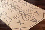 Close-up of the Hamid Washable Jutely Rug in natural jute with a dark brown geometric pattern on dark wood floors. Corner