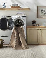 Hamid Washable Jutely Rug in a laundry room being washed in a front load washer. Camel rug with black pattern. Washing-Machine