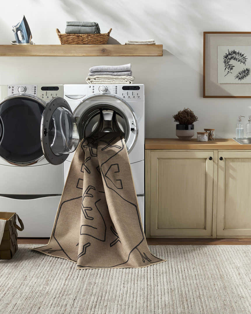 Hamid Washable Jutely Rug in a laundry room being washed in a front load washer. Camel rug with black pattern. Washing-Machine