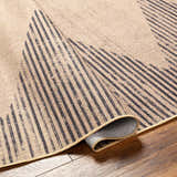 Close-up of the Ijlal Washable Area Rug in camel and dark brown, showing the texture and geometric stripe pattern. Fold