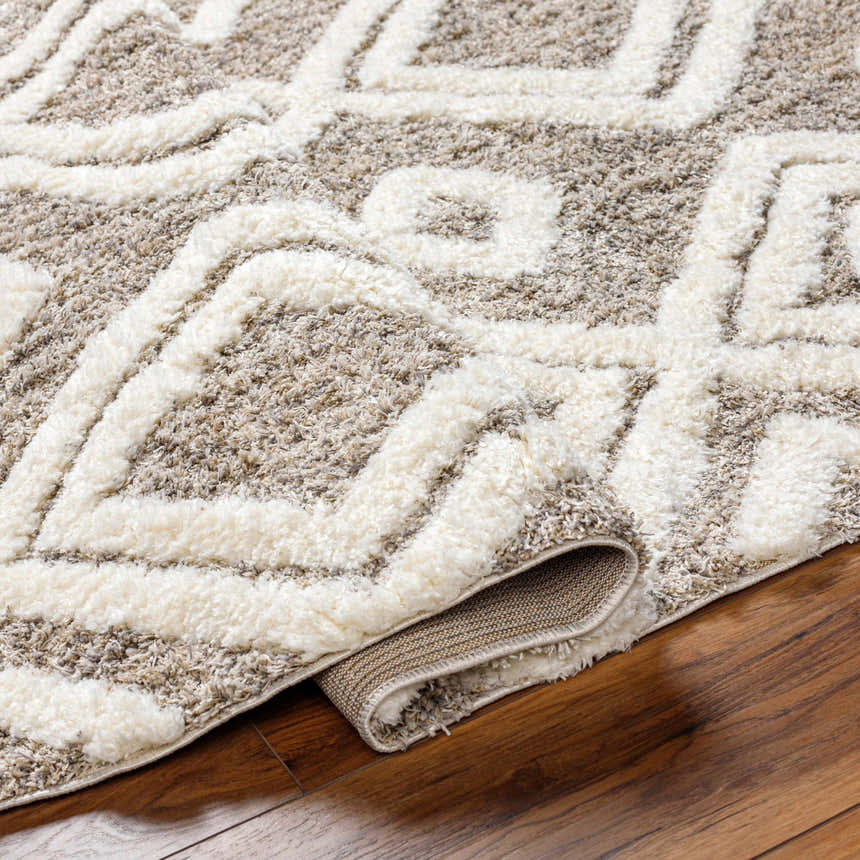 Close-up of the Nima Area Rug showing its bone and cloud gray geometric shag design and soft, plush texture. Fold