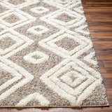 Close-up of the Nima Area Rug showing its bone and cloud gray geometric shag design and soft texture on a wood floor. Front