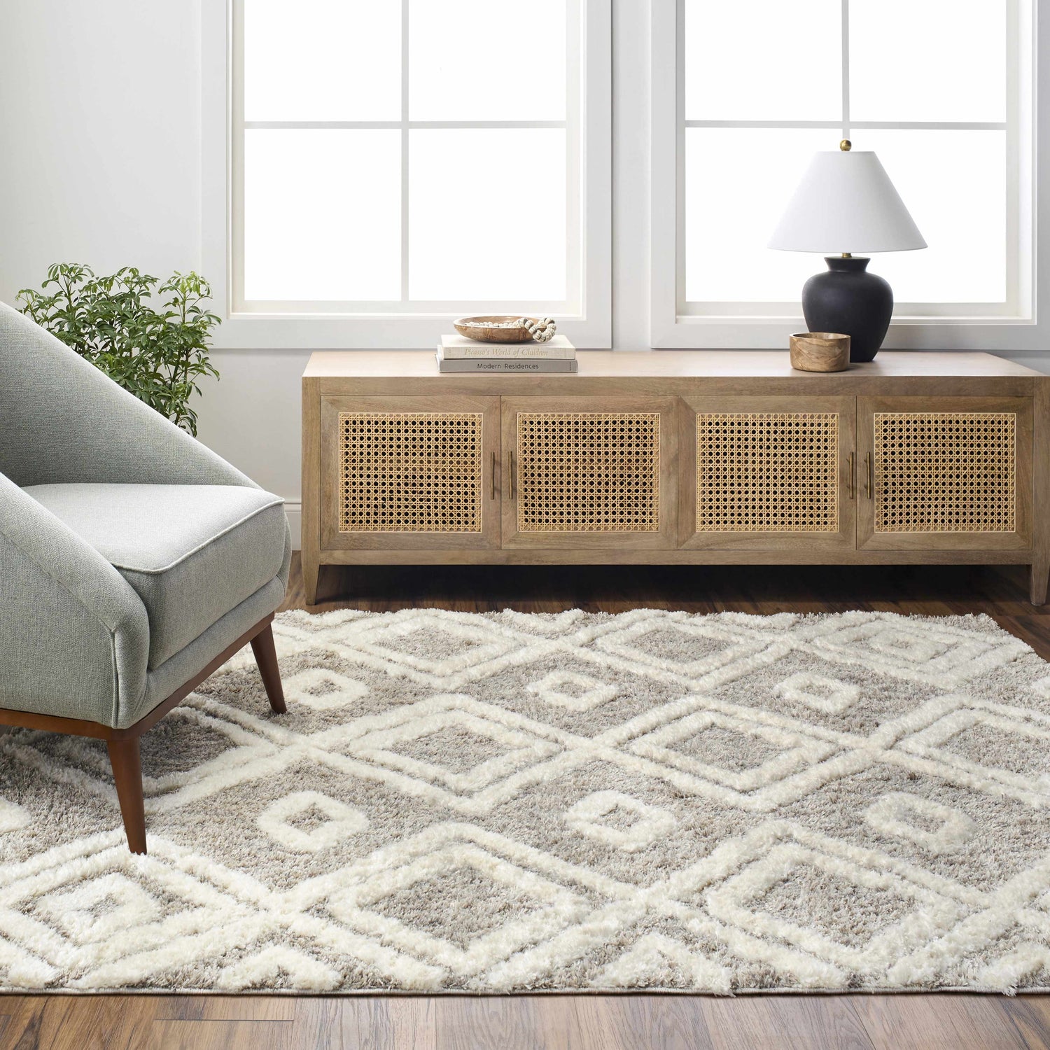 Living room scene with a bone and cloud gray Nima Area Rug, gray chair, and wooden cabinet. Roomscene-Rectangle