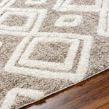 Close up of the Nima Area Rug showing its bone geometric pattern and shag texture on wood floor. Texture