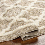 Close-up of the Yepa Tan Area Rug showing its geometric shag design and soft, neutral colors on hardwood floor. Fold