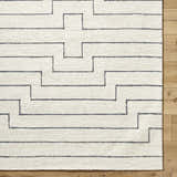 Close up of the hand-tufted Wyome Area Rug, an off-white wool rug with a geometric striped pattern. Corner