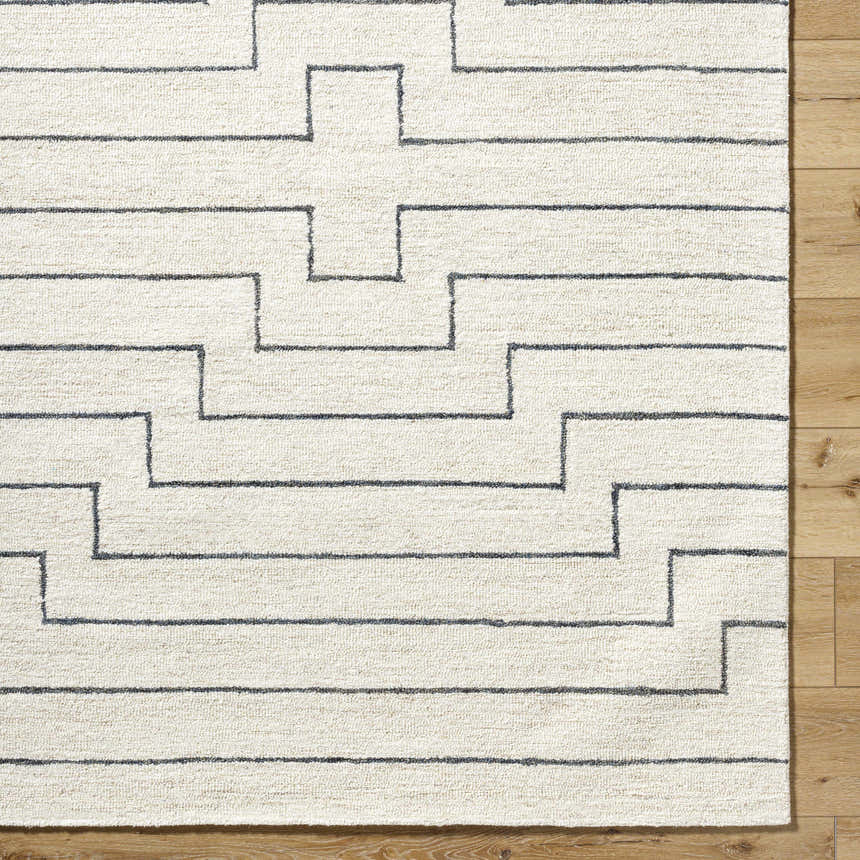 Close up of the hand-tufted Wyome Area Rug, an off-white wool rug with a geometric striped pattern. Corner