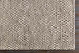Close up of the hand woven Sauget Area Rug with a textured, contemporary design. Black, gray, and off white. Corner