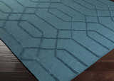 Close-up of the teal Sharps Area Carpet. Hand-knotted wool rug with a geometric pattern and subtle texture. Corner