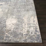 Close-up of the textured Shartlesville Luxe Rug in charcoal, gray, light gray, and taupe on a dark wood floor. Front