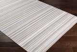 Close-up of the hand woven Shawville Area Rug, featuring brown, gray, tan, and white stripes on dark wood floors. Corner