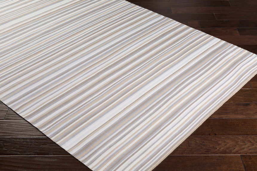 Close-up of the hand woven Shawville Area Rug, featuring brown, gray, tan, and white stripes on dark wood floors. Corner